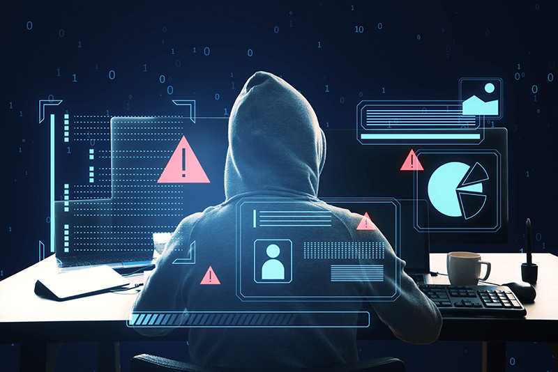 hooded hacker on computer with graphs and data and warning signs