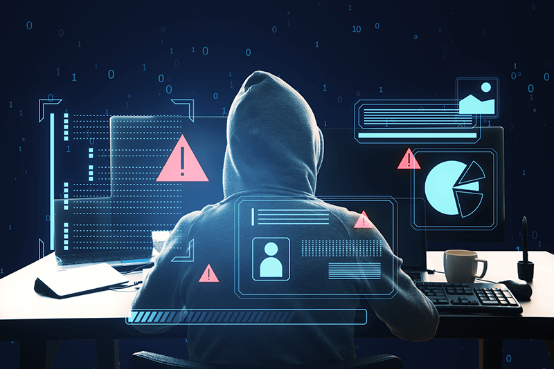 hooded hacker on computer with graphs and data and warning signs
