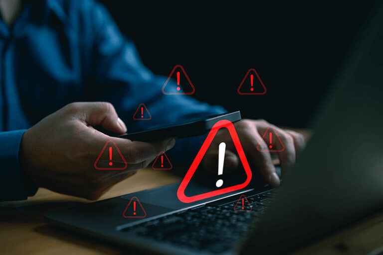 multiple red warning signs floating over a laptop and mobile phone